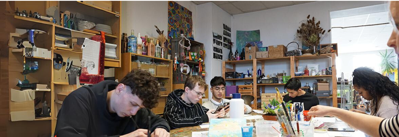 Gruppe von Schülern und Schülerinnen sitzen an einem runden Tisch und arbeiten konzentriert