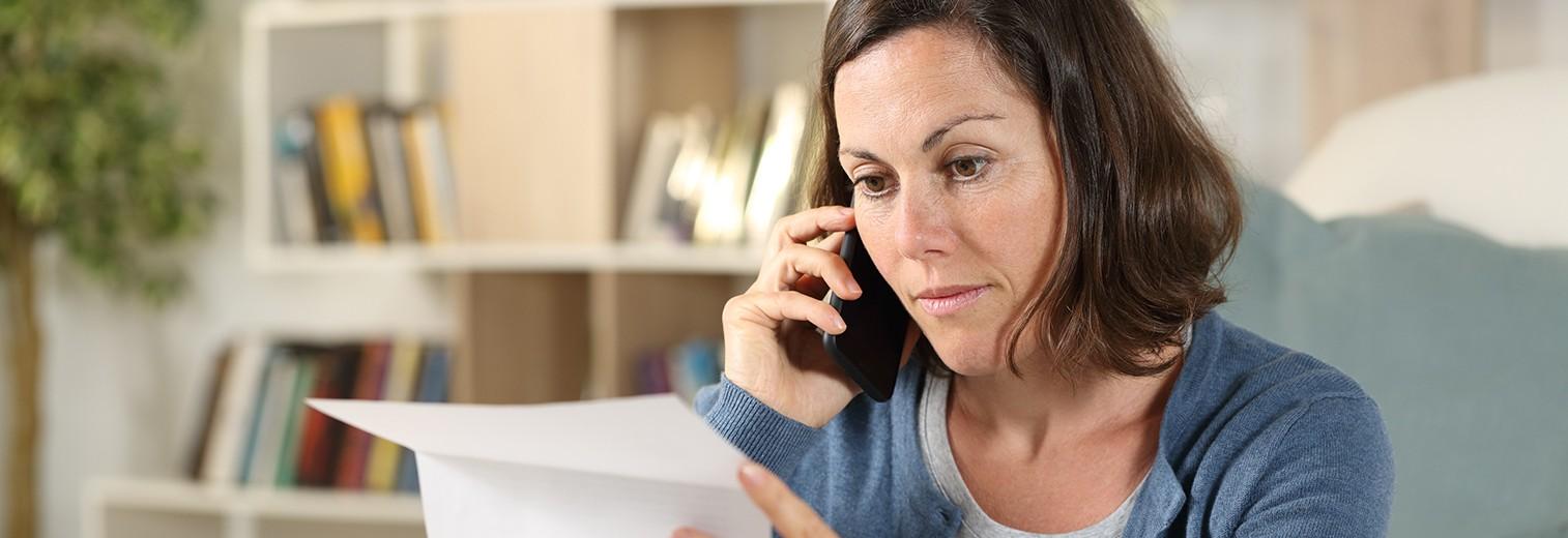 Frau mit einem Brief in der Hand am Telefon