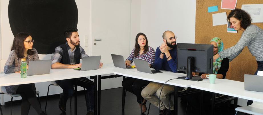 Lehrerin erklärt erwachsenen diversen Schülerinnen und Schülern etwas