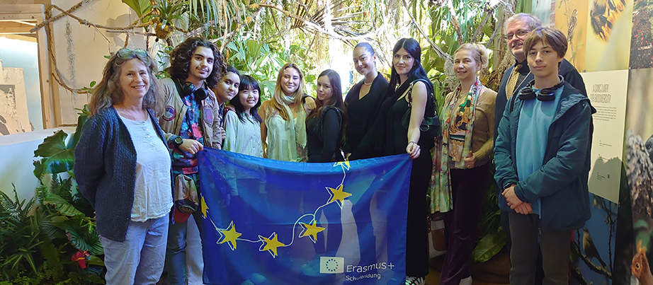 Schülerinnen und Schüler mit der Europaflagge im Gewächshaus