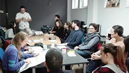 Lernende an einem Tisch hören Dozenten zu