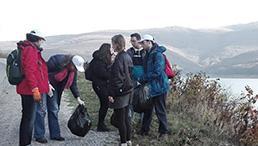 mehrere Menschen sammelm Müll in der Natur ein