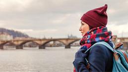 Frau mit Rucksack am Ufer eines Flusses mit Blick in die Ferne
