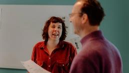 In einem Workshop für Lehrkräfte unterhalten sich eine Frau und ein Mann. Die Frau lächelt